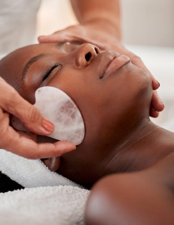 Esthetician using a Gua Sha stone on a woman's face during Gua Sha sculpting facial at, demonstrating the technique's ability to enhance facial contours and promote skin rejuvenation.
